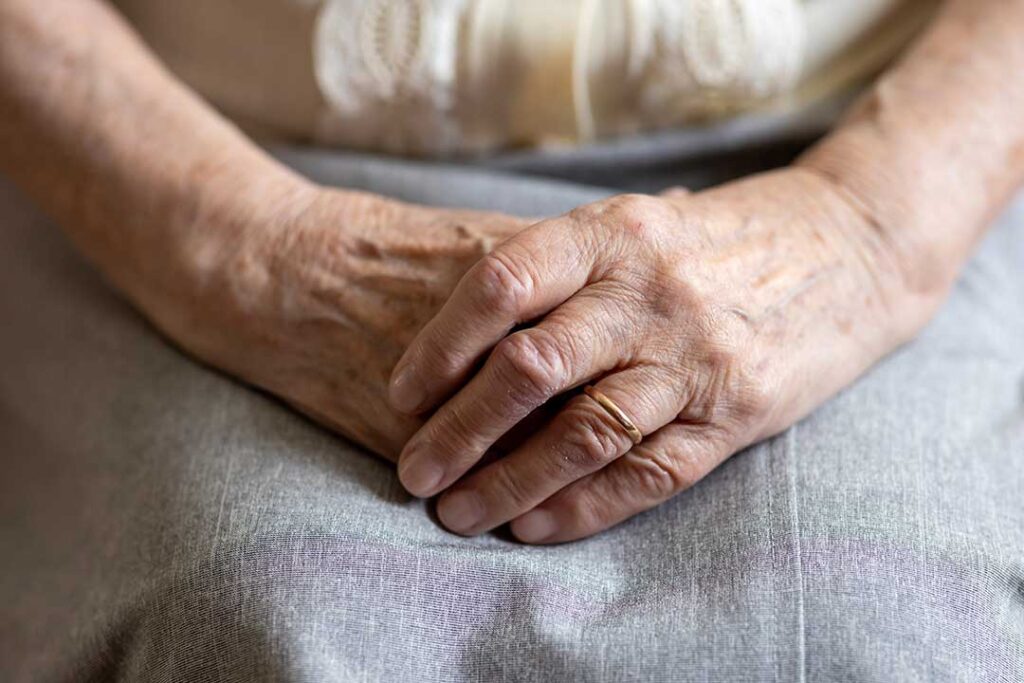Two senior adults sit at a kitchen table reviewing paperwork and discussing financial documents together.