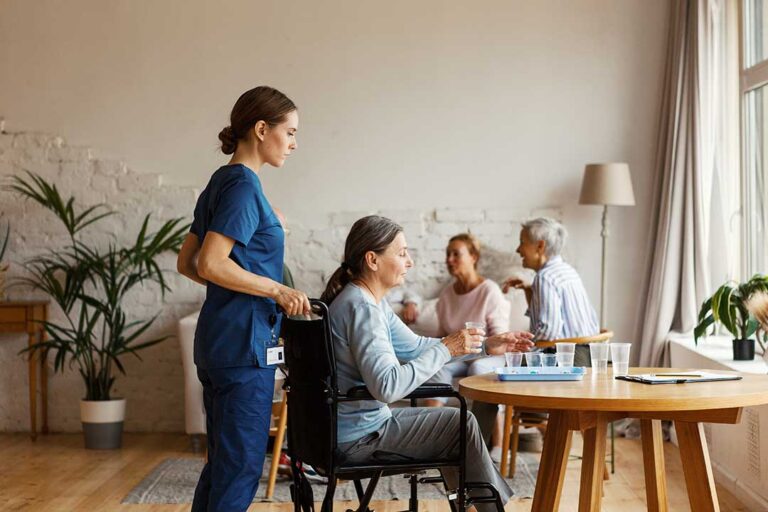 Older adult choosing clothing in a bright assisted living room with a caregiver nearby.