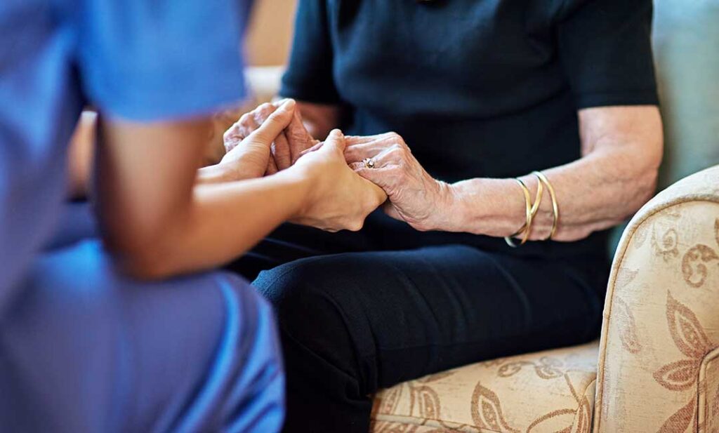Older adults sorting and packing boxes together in a cozy, well-lit living room.