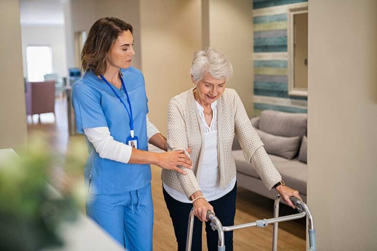 Older adults share a meal and conversation in a bright assisted living dining room.